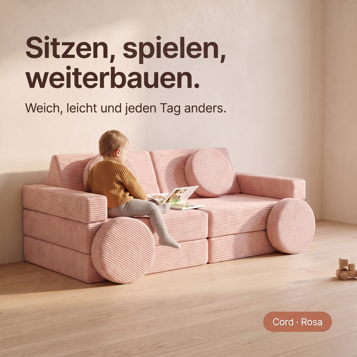 Sitzen, spielen, weiterbauen: Kind mit Bilderbuch auf dem Wuselsofa Basis, Cord Rosa