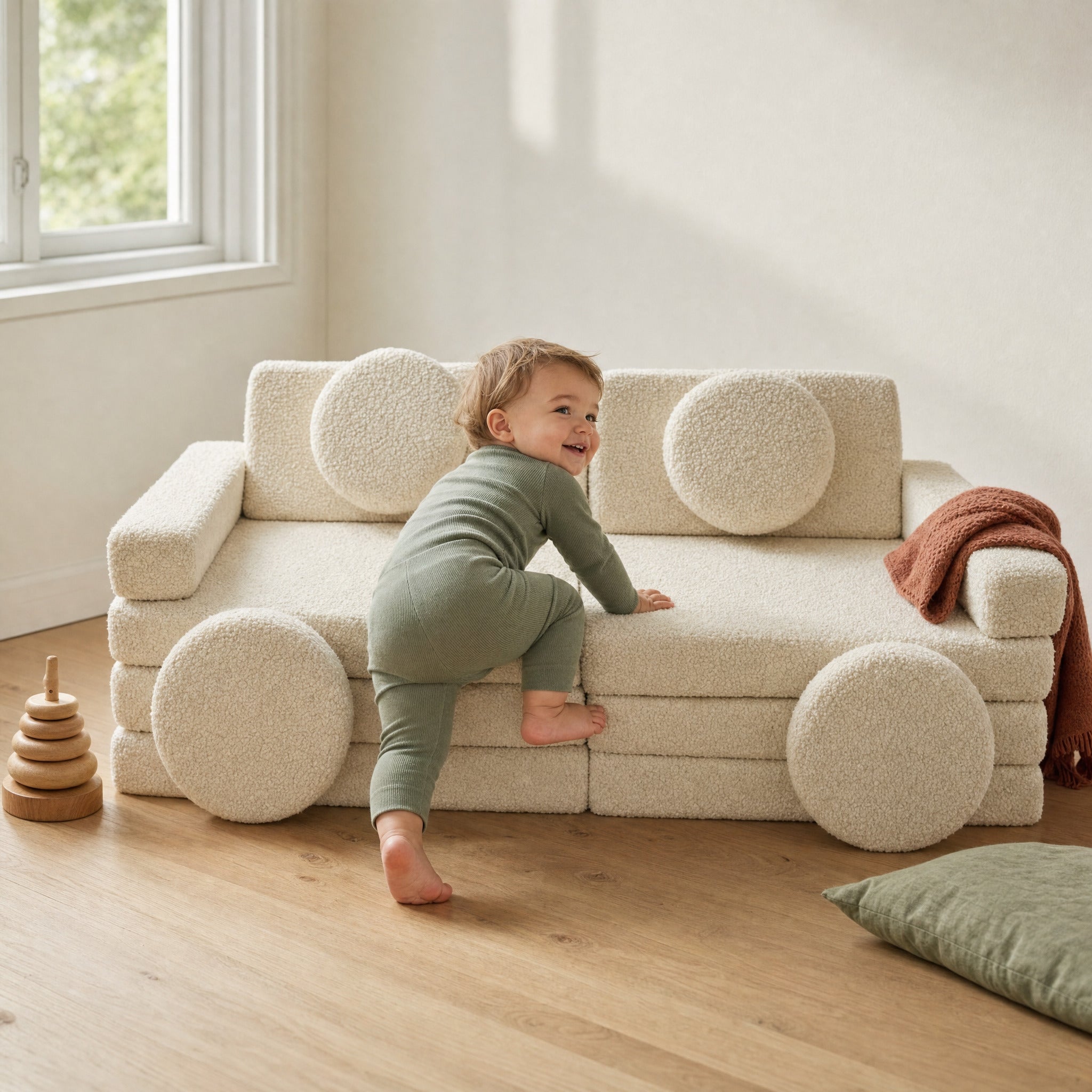 Kleinkind klettert auf das cremefarbene Spielsofa im Kinderzimmer